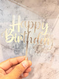 Clear acrylic Happy Birthday cake topper with "Happy Birthday" text, designed by Ward and Haneen for celebratory cakes.