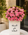 Pink roses and chocolates arrangement by Ward and Haneen featuring a bouquet of pink roses with chocolates in a decorative display.