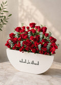 Luxurious red rose arrangement by Ward and Haneen featuring vibrant red roses and lush greenery in a stylish floral display.