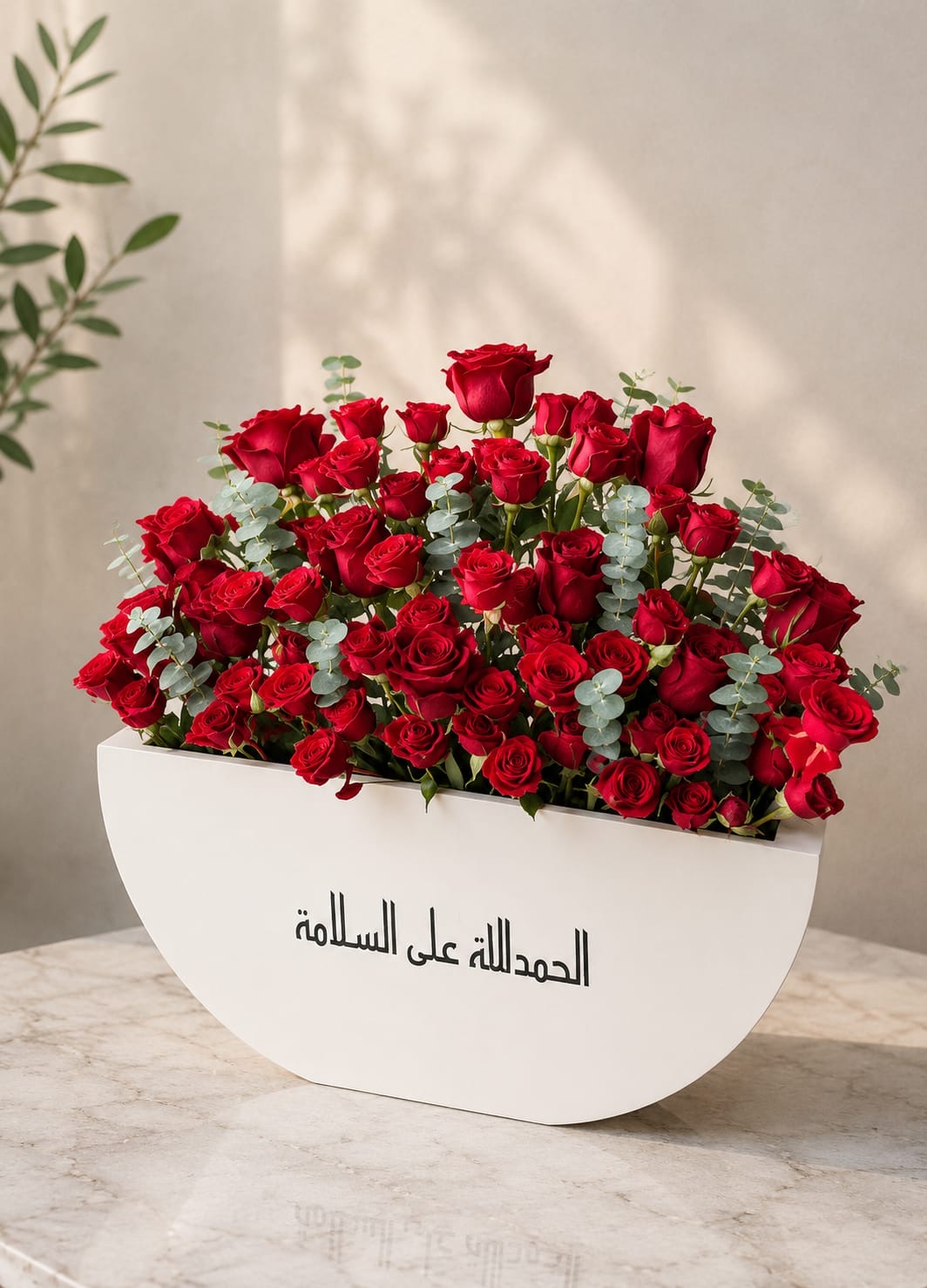 Luxurious red rose arrangement by Ward and Haneen featuring vibrant red roses and lush greenery in a stylish floral display.