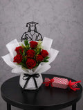 Red roses graduation bouquet with lush blooms and a box of chocolates, arranged beautifully for a graduation celebration.