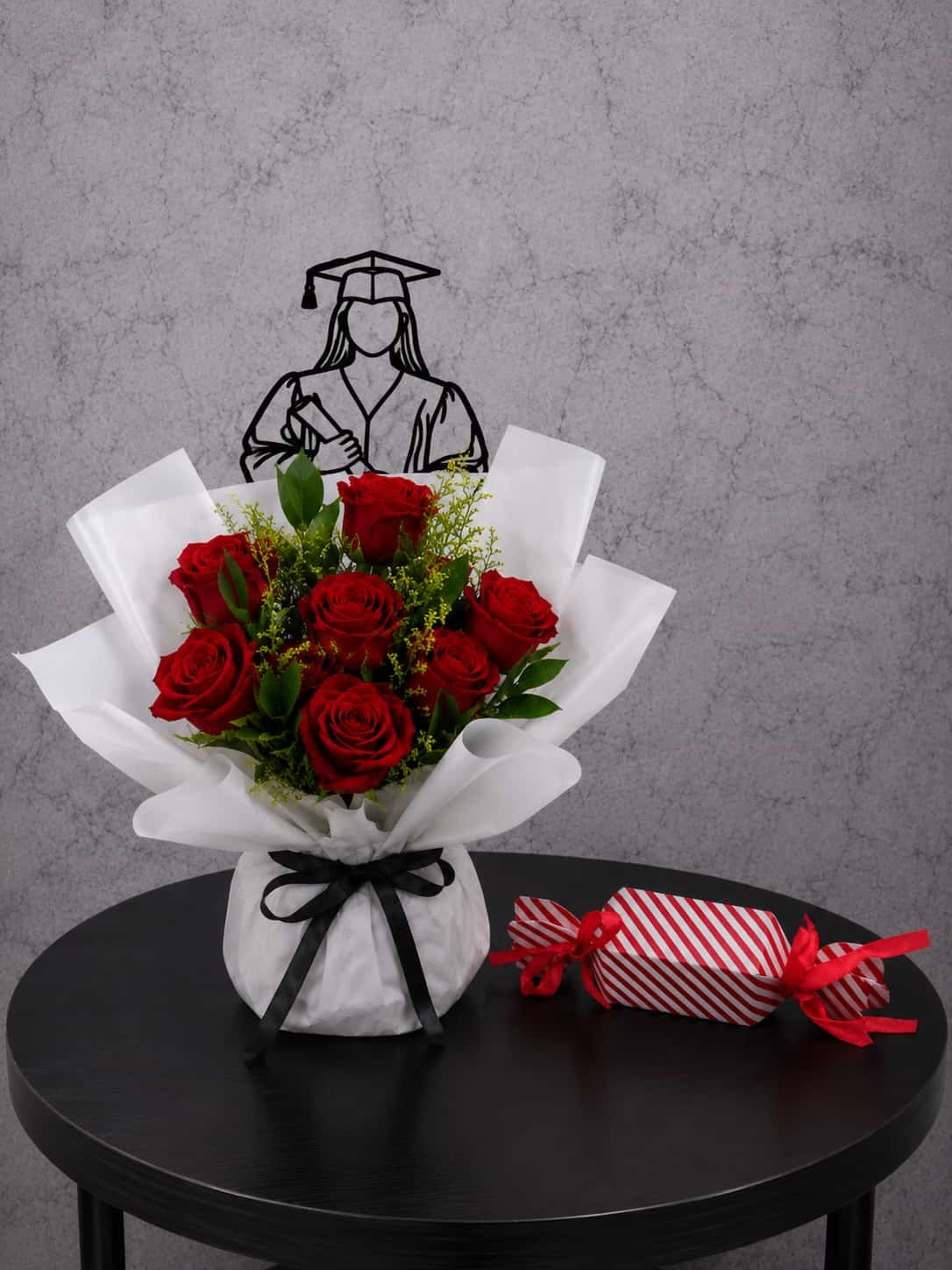 Red roses graduation bouquet with lush blooms and a box of chocolates, arranged beautifully for a graduation celebration.