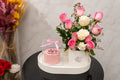 Pink roses and mini cake gift set by Ward and Haneen, featuring fresh flowers and a small decorated cake.