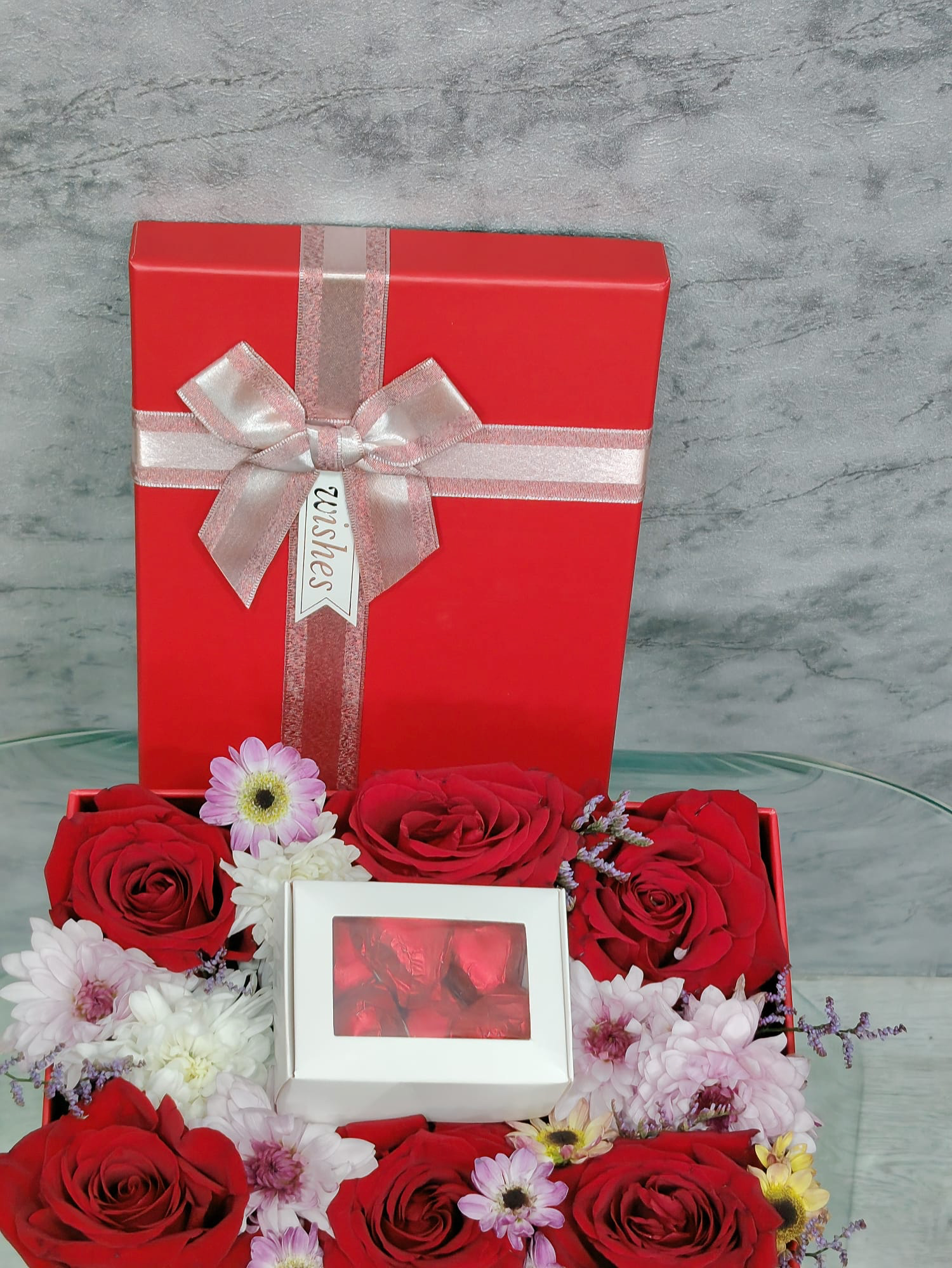 Six red roses and mixed flowers in a bouquet by Ward and Haneen, arranged beautifully in a 7-piece floral display.