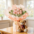 Blush rose and teddy bear gift set by Ward and Haneen, featuring a soft pink rose and a cuddly teddy bear on a decorative background.
