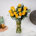 Yellow roses arranged in a clear glass vase, styled by Ward and Haneen, displayed against a neutral background.
