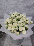 Crimson Deluxe 20 white baby roses bouquet wrapped with elegant paper by Ward and Haneen, showcasing delicate white roses.