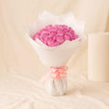 Pink flower bouquet with 25 blooms wrapped in white paper from Ward and Haneen.