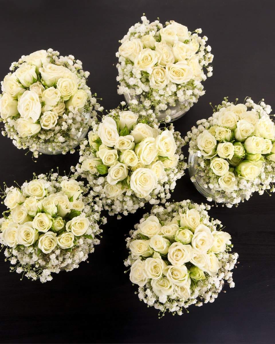 Mini Bliss white spray rose and Baby's Breath floral arrangement in clear glass vase by Ward and Haneen