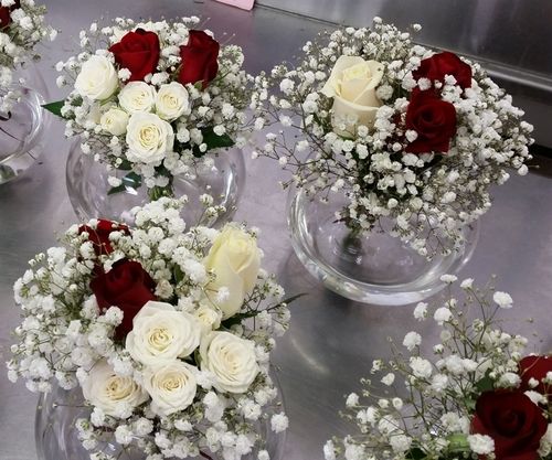 White spray rose and baby's breath floral arrangement in a clear glass vase by Ward and Haneen, displayed on a white background.