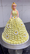 Yellow cake designed to resemble a doll with floral decorations on a marble surface.