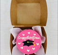 Pink graduation heart mini bento cake by Ward and Haneen, featuring a decorated small cake with a graduation theme and heart design.