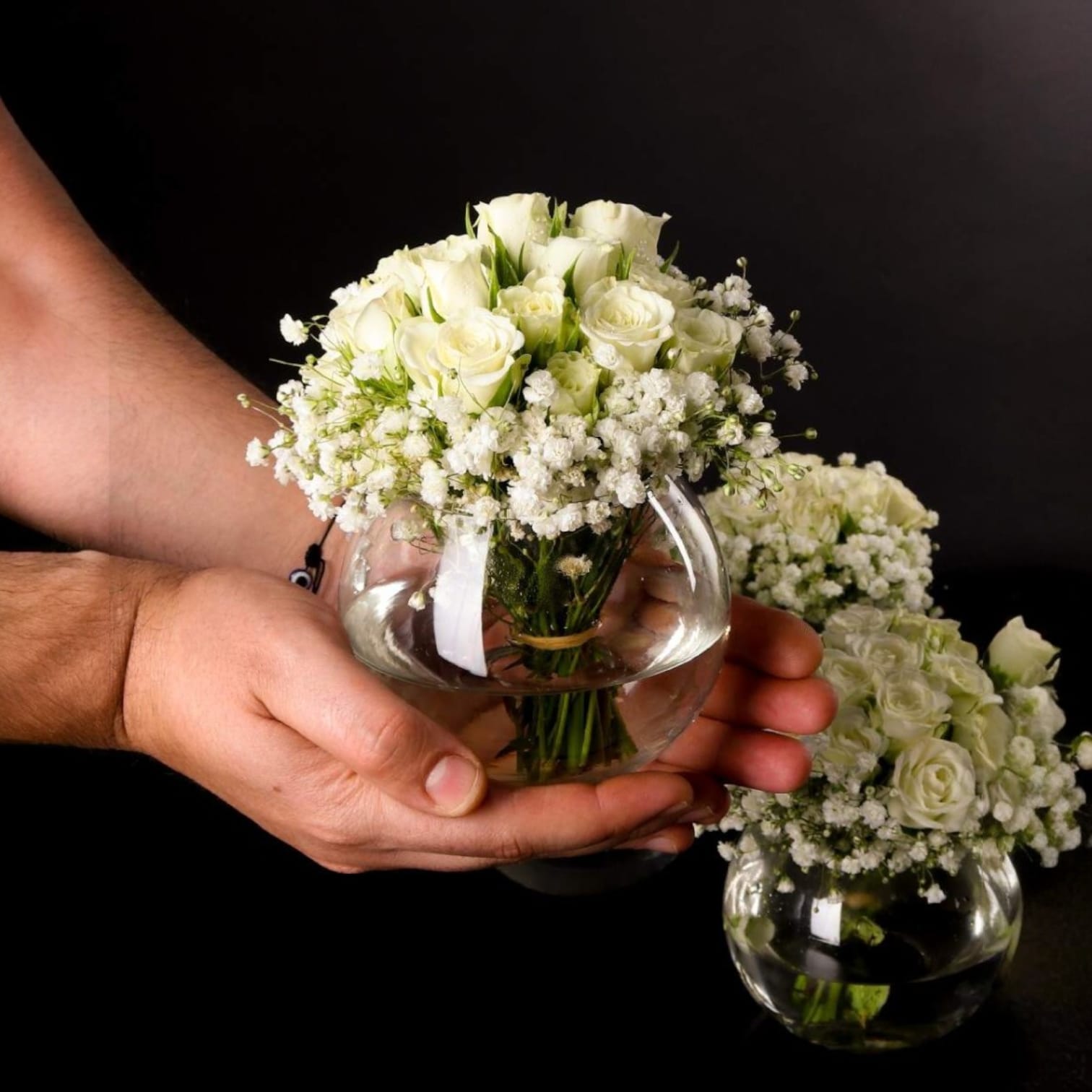 White spray rose and baby's breath floral arrangement in a small Ward and Haneen glass vase, styled for a delicate, elegant look.