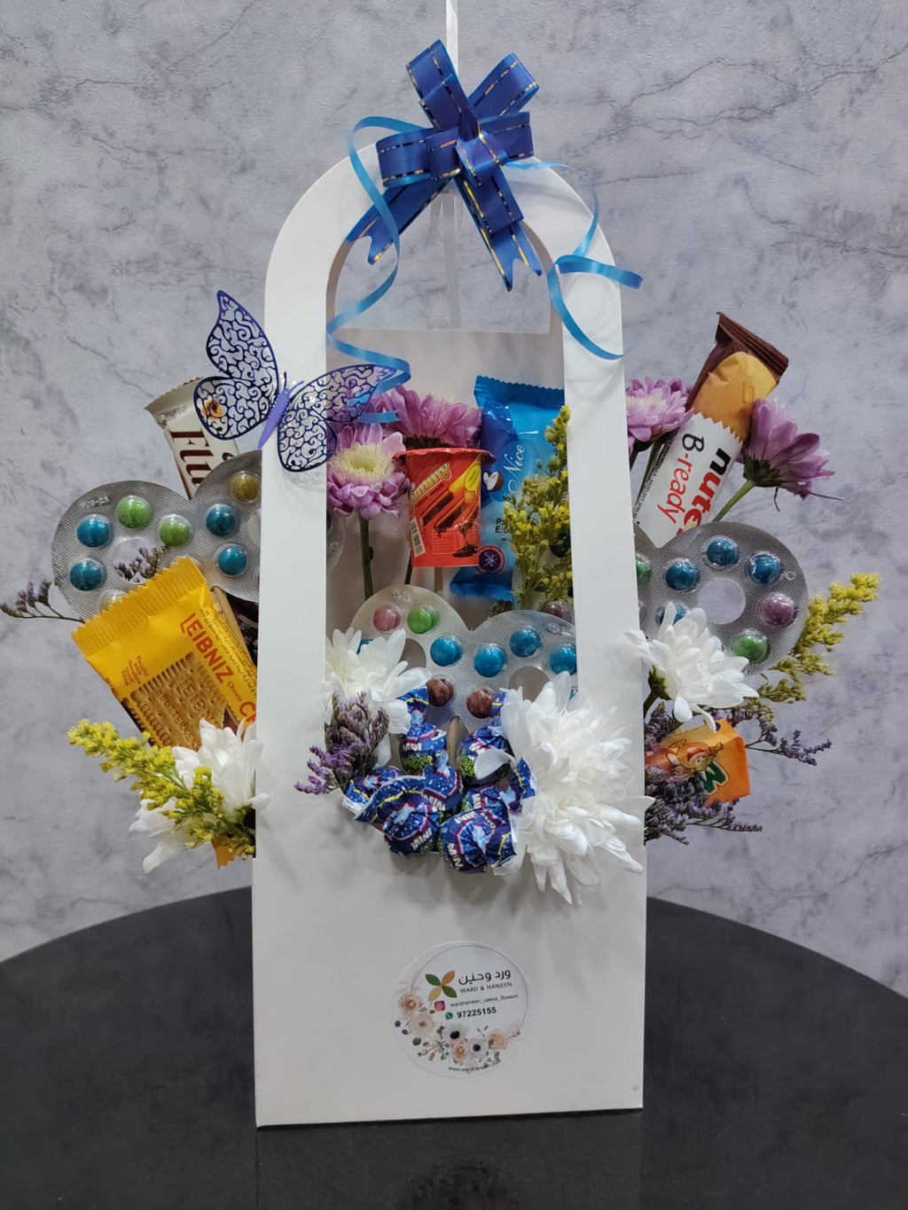 Blue balloon and chocolate gift basket by Ward and Haneen featuring assorted chocolates and colorful decorations.