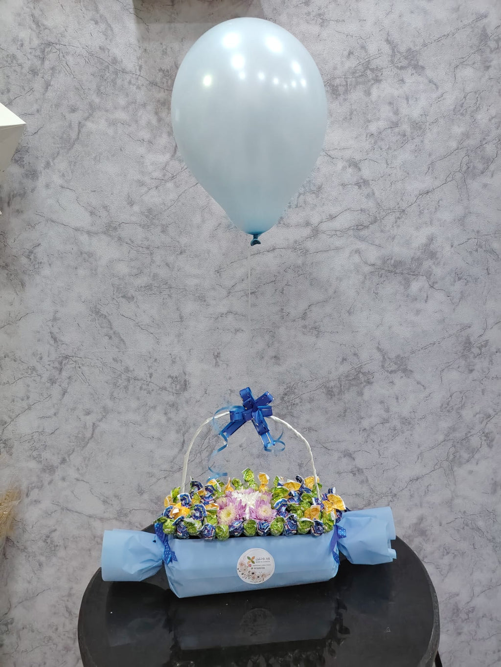 Deluxe chocolate gift box from Ward and Haneen with blue balloons, featuring assorted chocolates and elegant packaging.