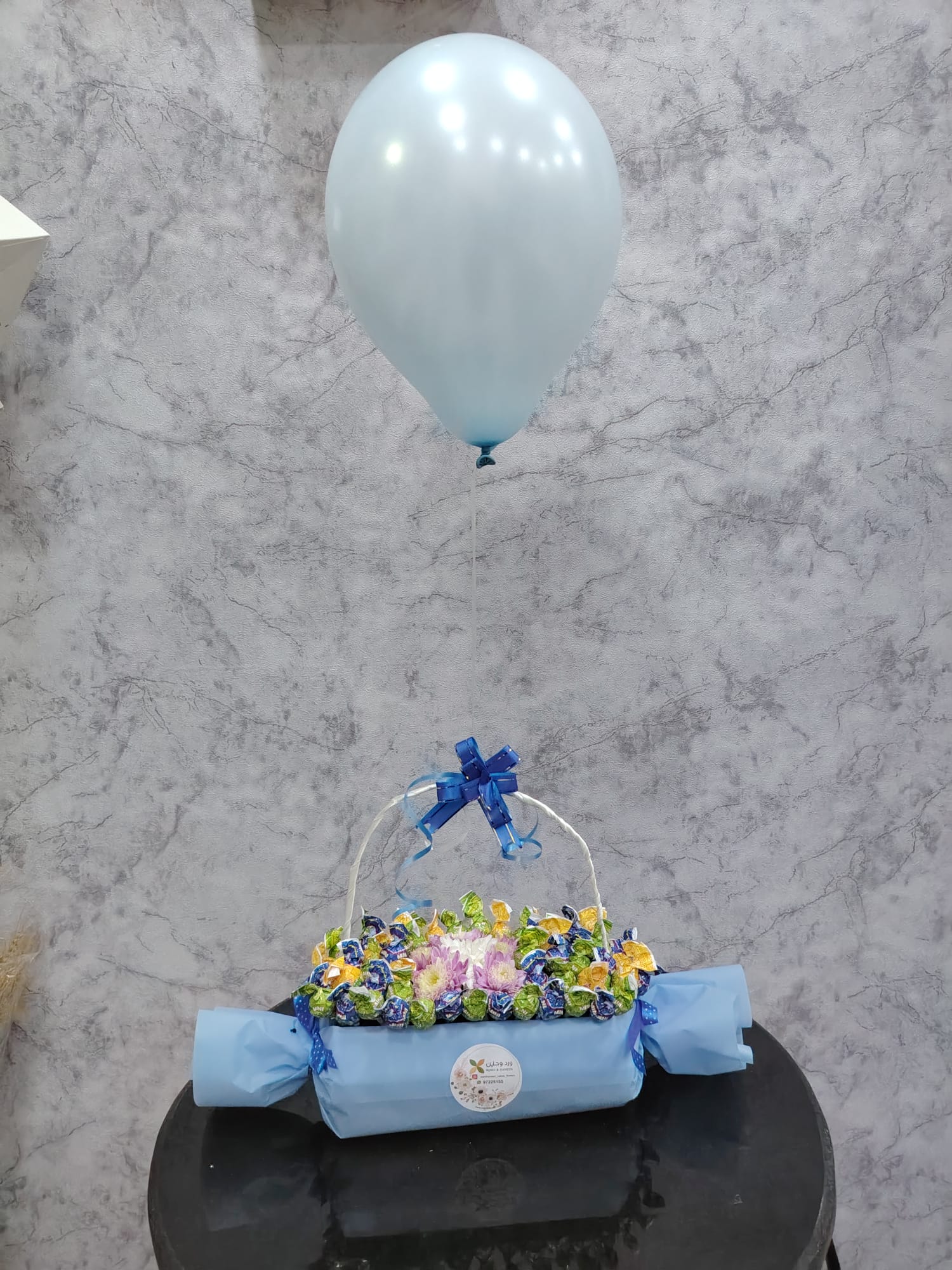 Deluxe chocolate gift box from Ward and Haneen with blue balloons, featuring assorted chocolates and elegant packaging.