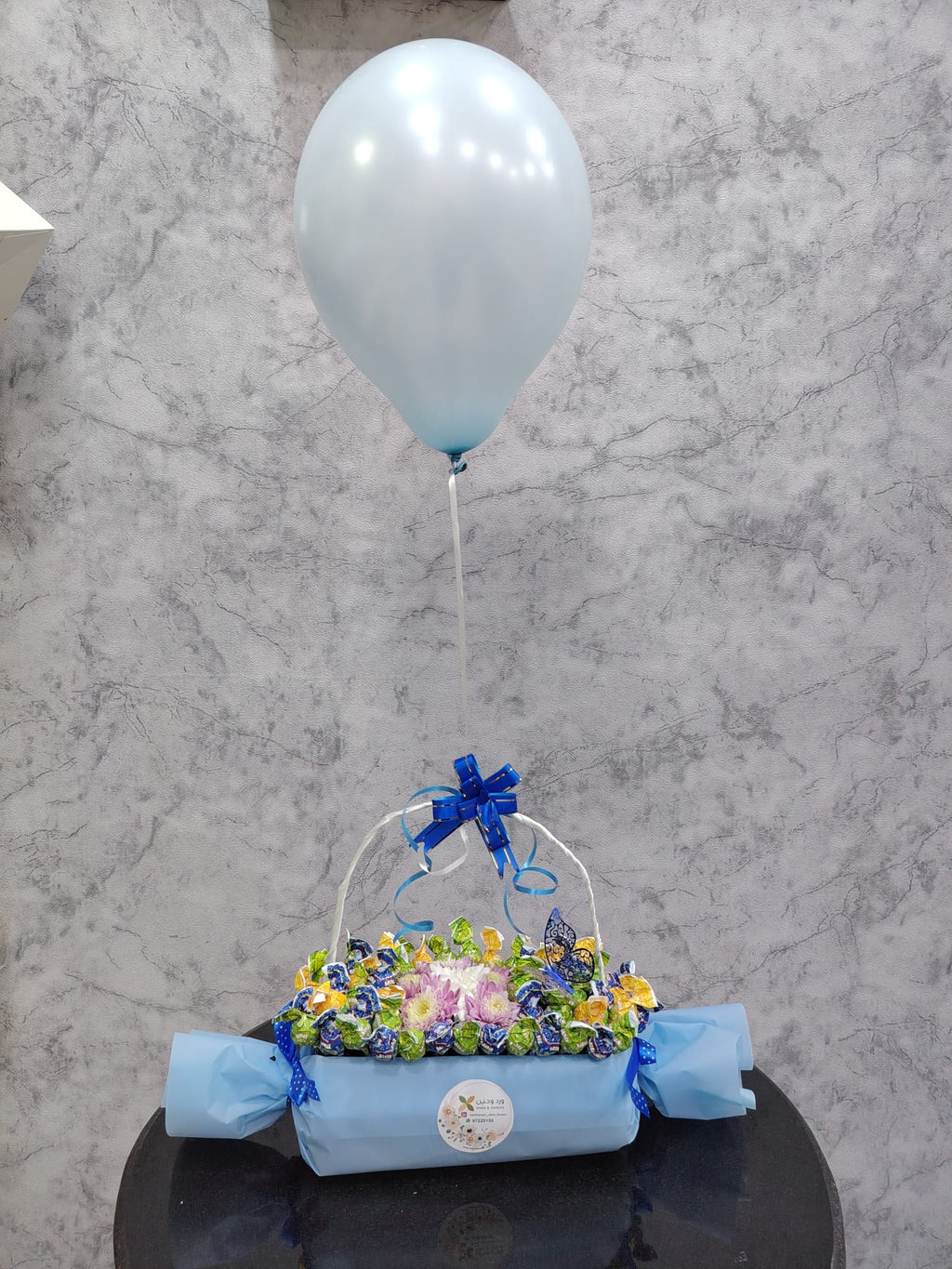 Deluxe chocolate gift box from Ward and Haneen with blue balloons, featuring assorted chocolates and elegant packaging.