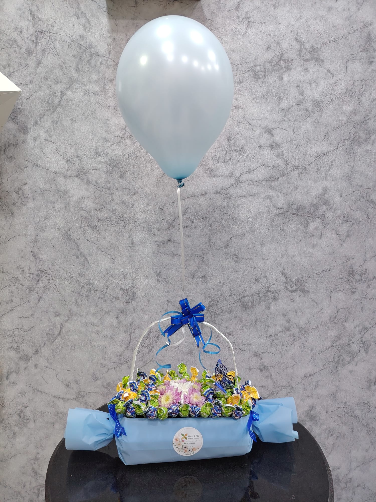 Deluxe chocolate gift box from Ward and Haneen with blue balloons, featuring assorted chocolates and elegant packaging.
