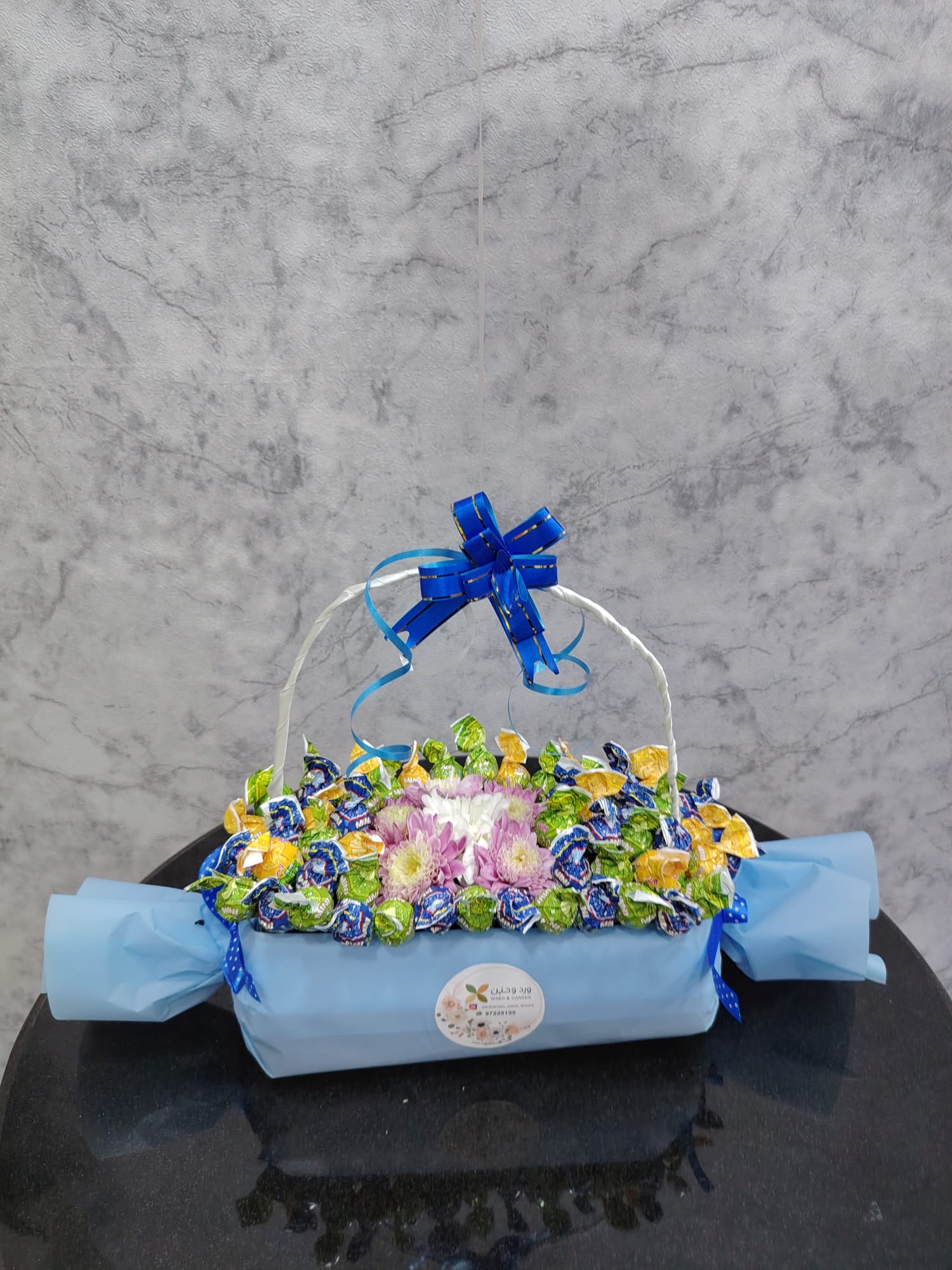 Deluxe chocolate gift box from Ward and Haneen with blue balloons, featuring assorted chocolates and elegant packaging.