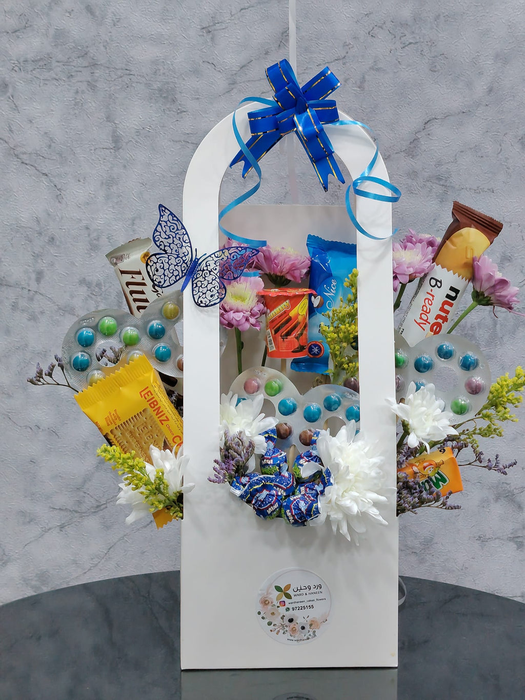 Blue balloon-shaped chocolate gift basket by Ward and Haneen with assorted chocolates and decorative blue balloons.